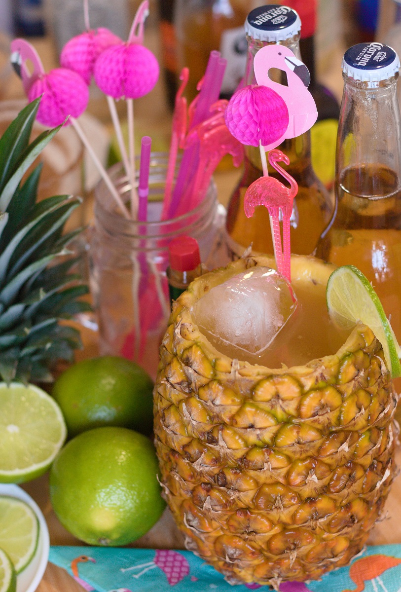 Michelada de piña cocktail surrounded by ingredients